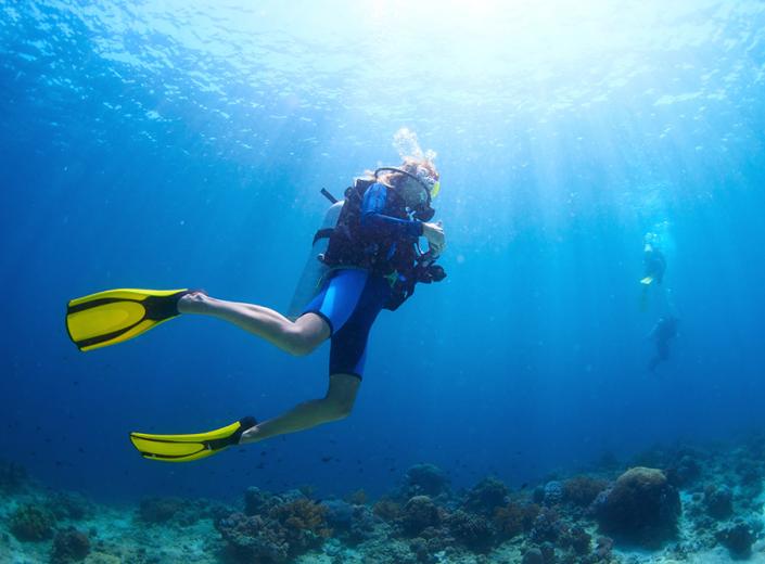 Subacqueo esplora il fondale marino con pinne gialle e attrezzatura da immersione.